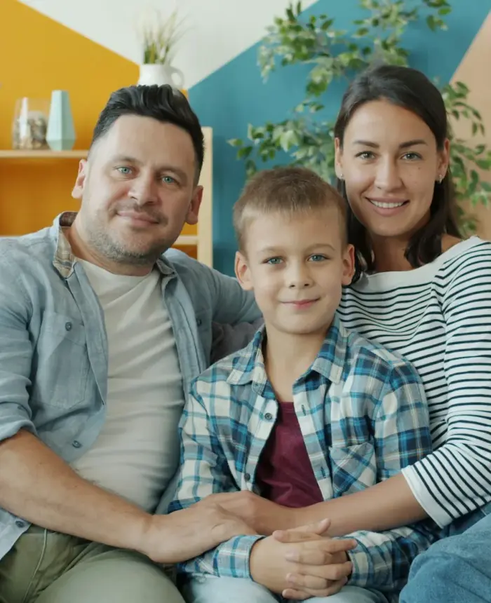 Adoptive parents and their son sitting close together at home